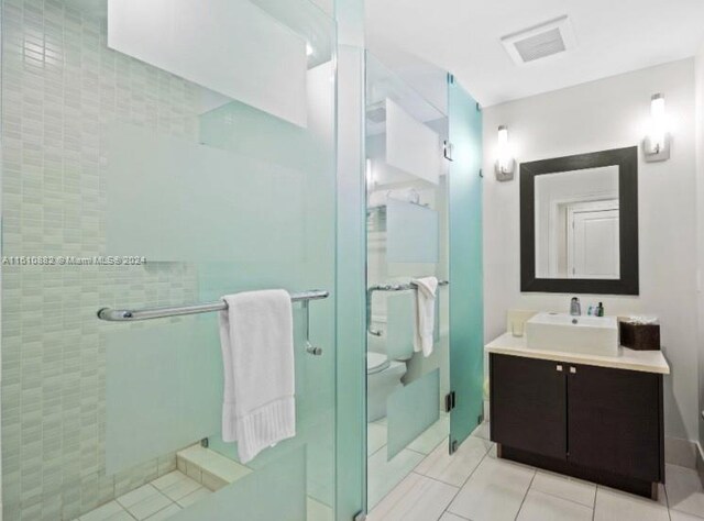 bathroom with vanity with extensive cabinet space, walk in shower, tile flooring, and toilet