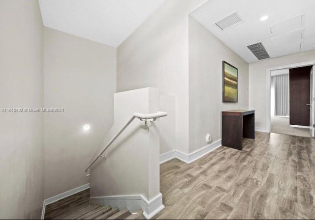 stairway featuring wood finished floors, visible vents, and baseboards