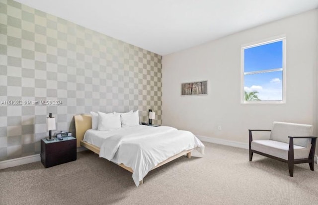 bedroom featuring an accent wall, carpet flooring, baseboards, and wallpapered walls