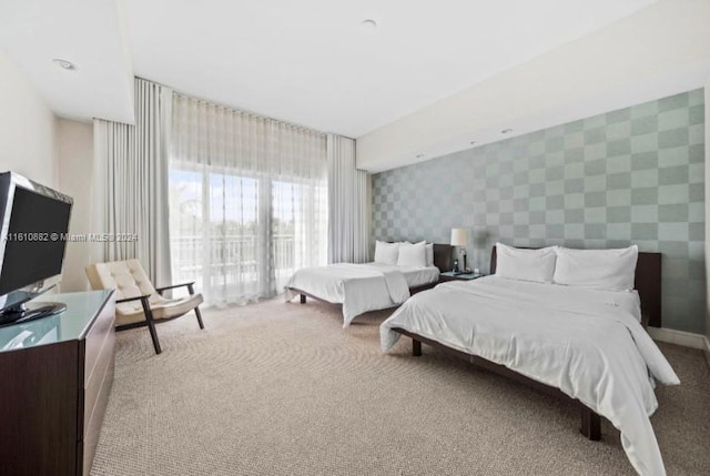 carpeted bedroom featuring an accent wall, baseboards, and wallpapered walls