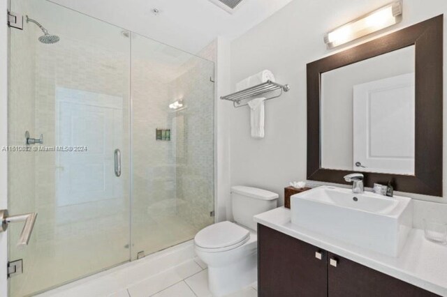 bathroom featuring tile flooring, oversized vanity, toilet, and walk in shower