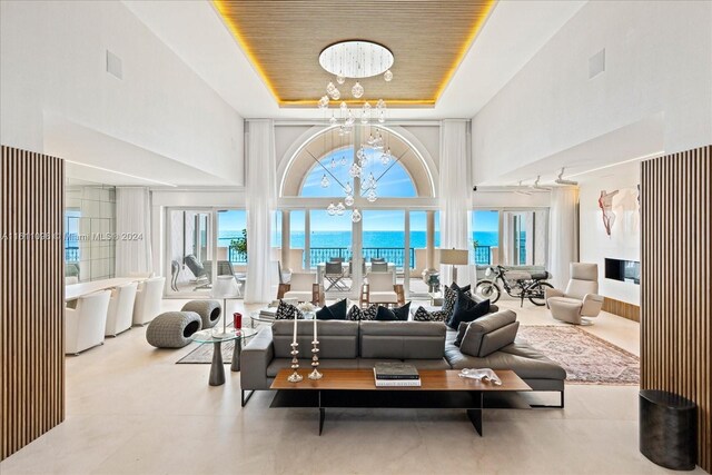 interior space featuring an inviting chandelier, wooden ceiling, a high ceiling, and a tray ceiling