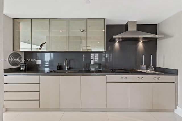 kitchen with sink, light tile patterned flooring, tasteful backsplash, and wall chimney range hood