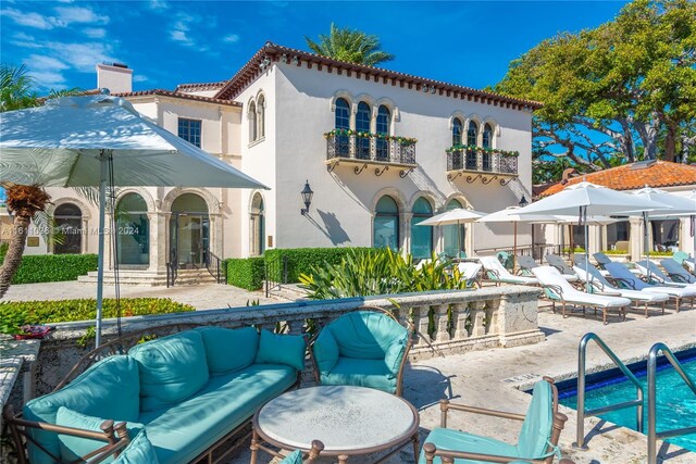 rear view of house with a patio, outdoor lounge area, and a community pool