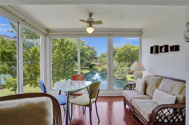 sunroom featuring ceiling fan and a water view