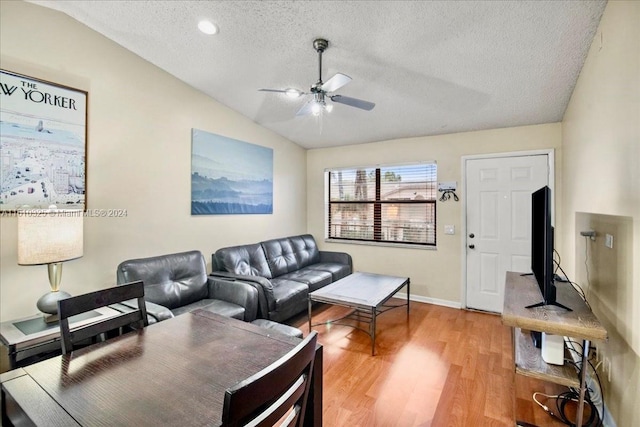 living room featuring light wood-type flooring, a textured ceiling, ceiling fan, and lofted ceiling