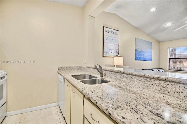 kitchen with light stone counters, a textured ceiling, sink, light tile patterned floors, and lofted ceiling