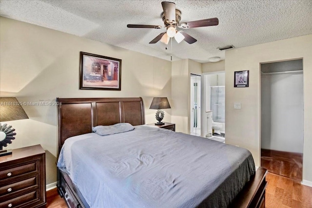 bedroom featuring a textured ceiling, light hardwood / wood-style flooring, ensuite bath, and ceiling fan