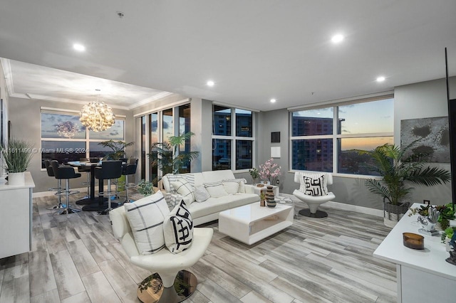 living room with crown molding, light hardwood / wood-style flooring, expansive windows, a chandelier, and plenty of natural light