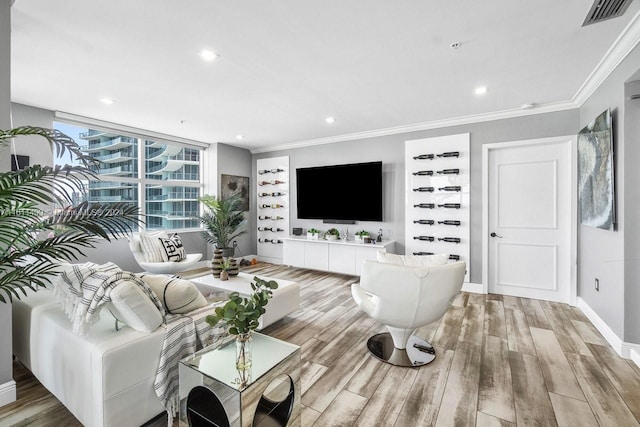 living area with crown molding, baseboards, visible vents, and light wood-style floors