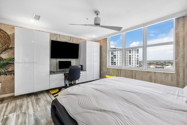 bedroom featuring ornamental molding, built in desk, wood finished floors, and visible vents