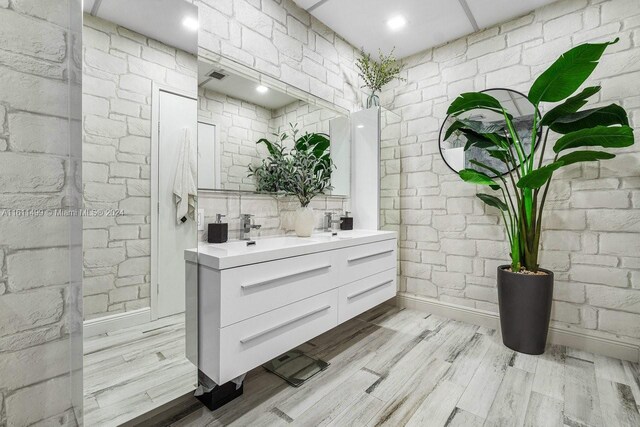 bathroom featuring wood-type flooring, oversized vanity, and double sink