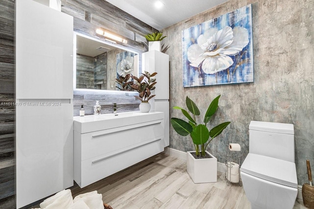 bathroom with toilet, wood finished floors, and vanity