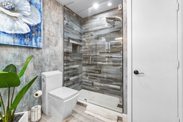 bathroom with a shower with shower door and toilet