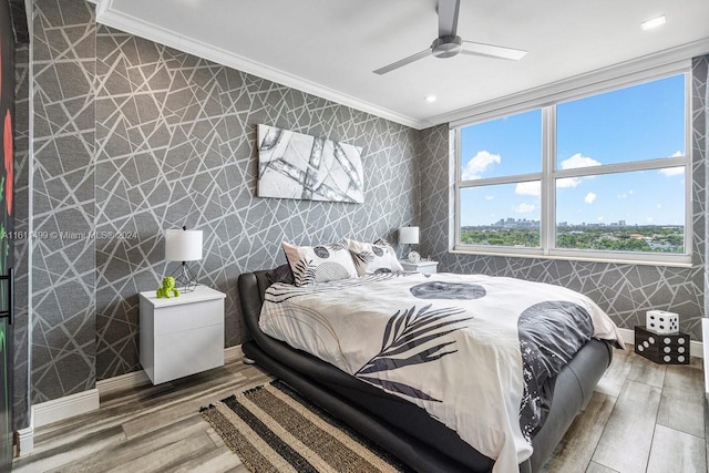 bedroom featuring wallpapered walls, baseboards, ornamental molding, and wood finished floors