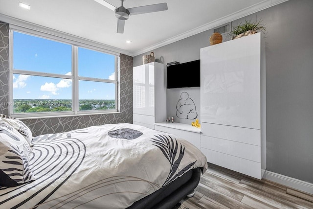 bedroom with ceiling fan, wood finished floors, visible vents, baseboards, and crown molding