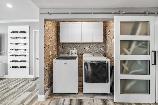 clothes washing area with light wood finished floors, washing machine and clothes dryer, and cabinet space