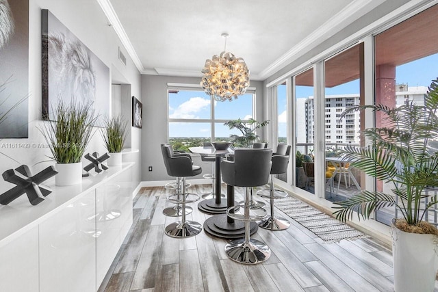 dining space with ornamental molding, visible vents, plenty of natural light, and wood finished floors