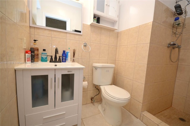 bathroom featuring vanity, tile walls, a tile shower, toilet, and tile patterned flooring