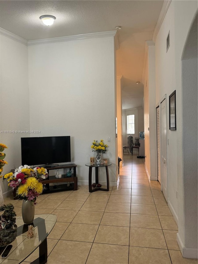 corridor featuring light tile patterned flooring, ornamental molding, and a textured ceiling