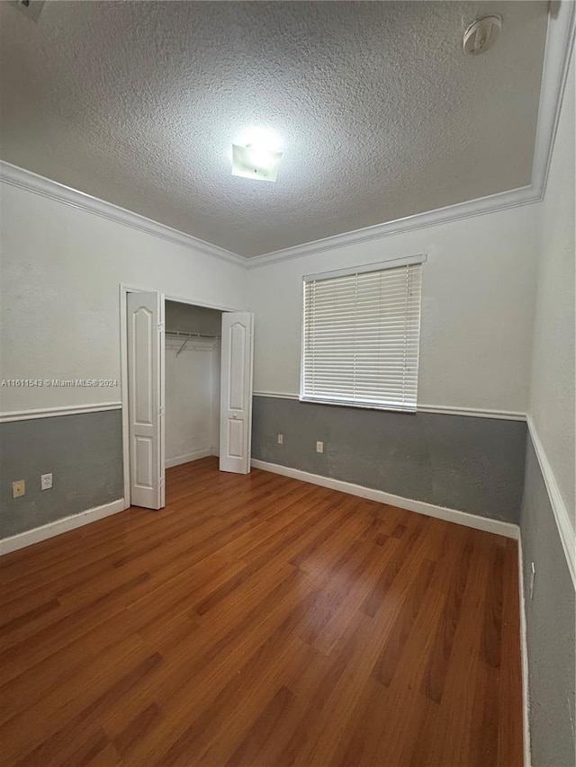 unfurnished bedroom with a closet, crown molding, hardwood / wood-style floors, and a textured ceiling