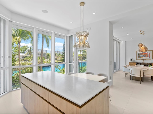 kitchen with decorative light fixtures, a healthy amount of sunlight, light tile floors, and a kitchen island