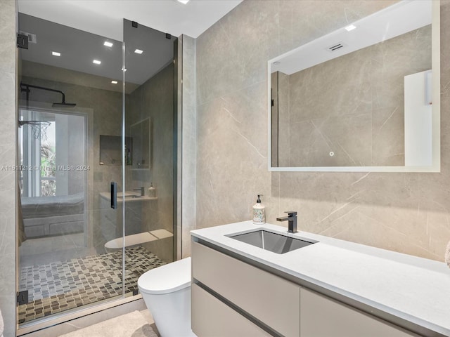 bathroom with an enclosed shower, oversized vanity, toilet, and tile walls