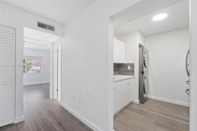 hallway with stacked washing maching and dryer and light hardwood / wood-style floors