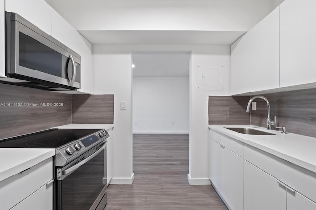 kitchen featuring white cabinetry, decorative backsplash, electric range, and sink