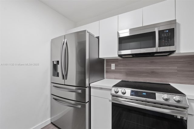 kitchen with hardwood / wood-style floors, white cabinetry, appliances with stainless steel finishes, and tasteful backsplash