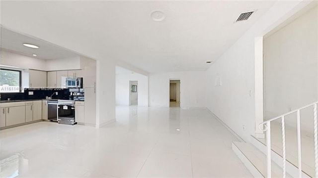 interior space featuring appliances with stainless steel finishes, backsplash, and light tile patterned floors