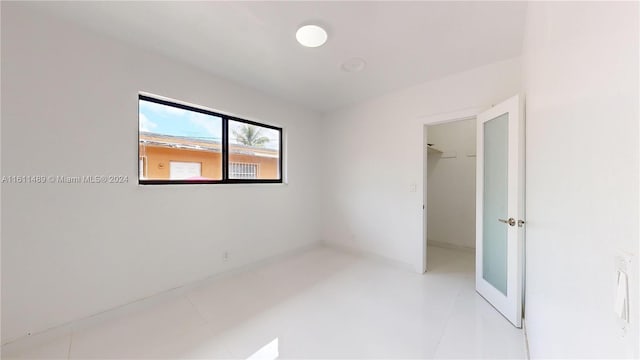 unfurnished bedroom featuring a spacious closet, a closet, and light tile patterned floors