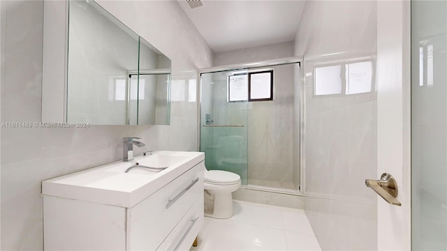 bathroom with vanity, toilet, tile patterned floors, and a shower with door