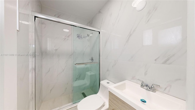 bathroom with vanity, toilet, tile walls, and an enclosed shower