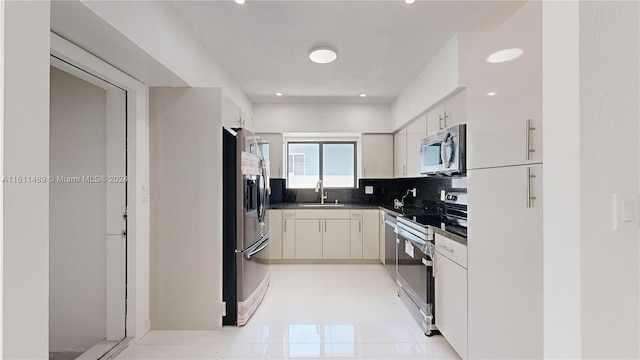 kitchen with appliances with stainless steel finishes, light tile patterned flooring, sink, and backsplash