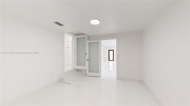 tiled spare room with french doors