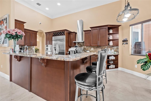 kitchen with wall chimney range hood, kitchen peninsula, stainless steel appliances, backsplash, and light tile floors