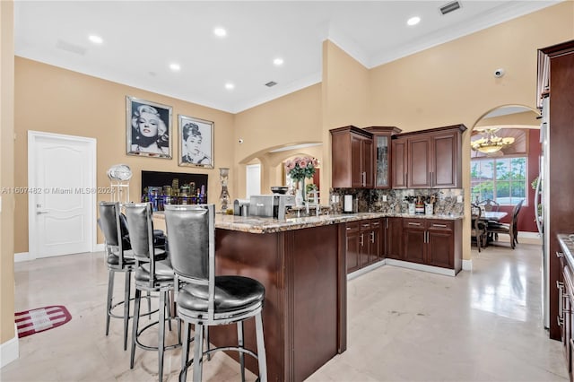 kitchen with light stone countertops, kitchen peninsula, light tile flooring, backsplash, and a kitchen bar