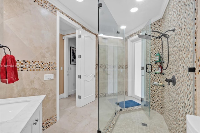 bathroom with ornamental molding, a shower with shower door, vanity, and tile walls