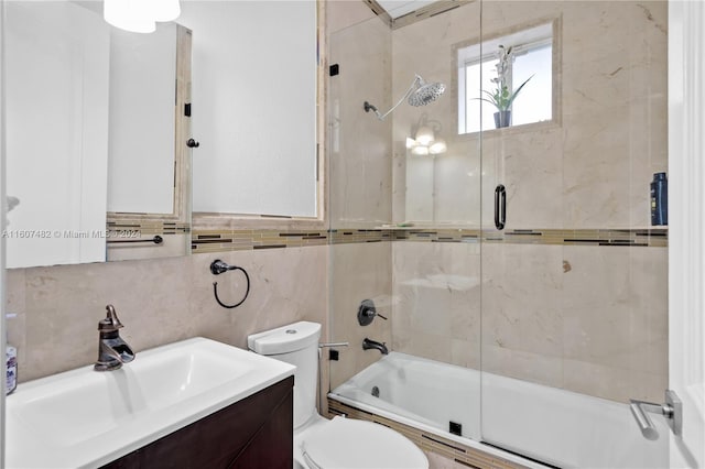 full bathroom with enclosed tub / shower combo, vanity, toilet, and tile walls