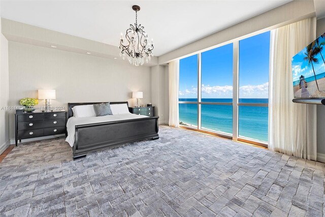 bedroom featuring access to exterior, an inviting chandelier, and a water view