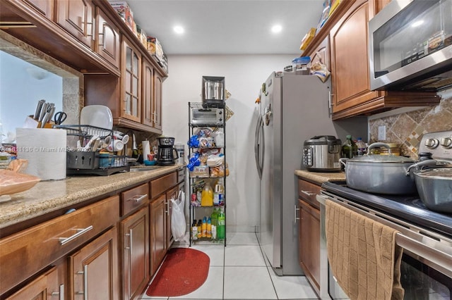 kitchen featuring decorative backsplash, light tile patterned flooring, light stone counters, and appliances with stainless steel finishes