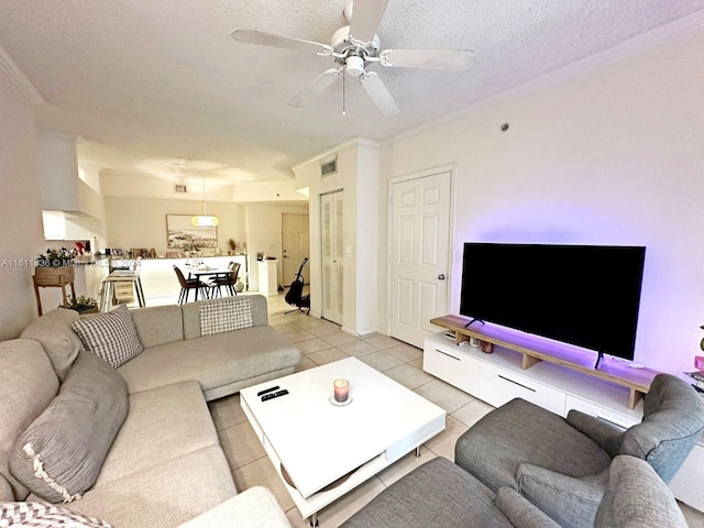 living room featuring ceiling fan, crown molding, light tile patterned floors, and a textured ceiling