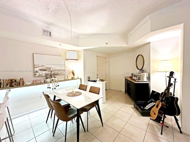 tiled dining area featuring ornamental molding, a textured ceiling, and a tray ceiling