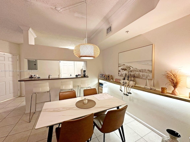 dining room featuring light tile patterned flooring, ornamental molding, and a textured ceiling