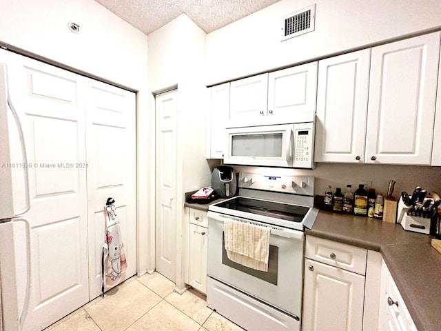 kitchen featuring a textured ceiling, light tile patterned floors, white cabinets, and white appliances