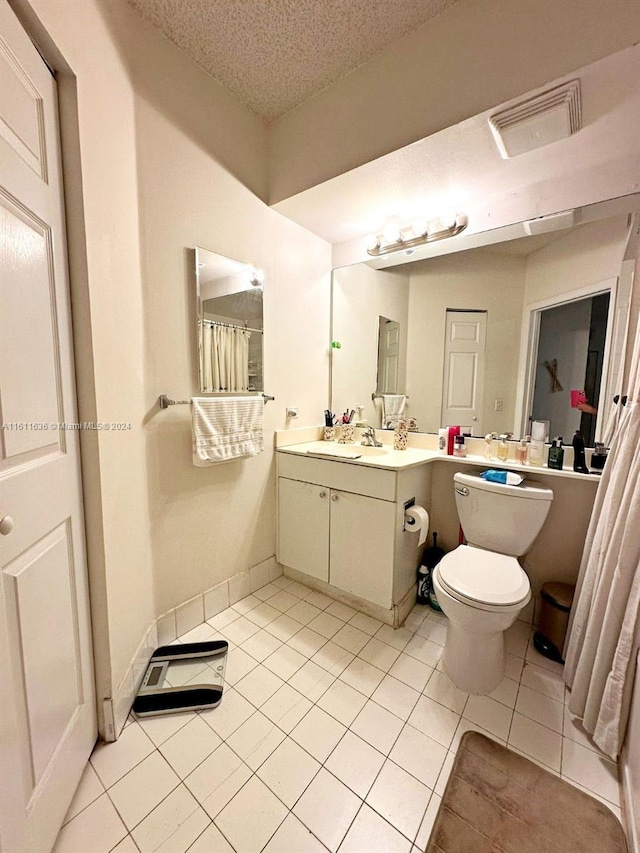 bathroom with tile patterned floors, vanity, a textured ceiling, and toilet