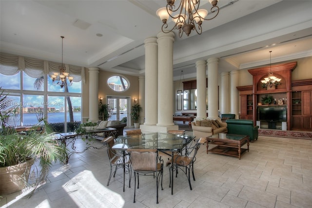 dining space with decorative columns, ornamental molding, a raised ceiling, a water view, and a notable chandelier