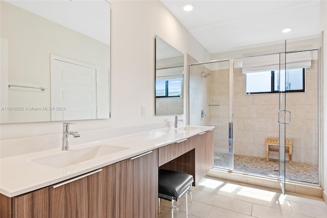 bathroom featuring tile flooring, double vanity, a shower with shower door, and a wealth of natural light