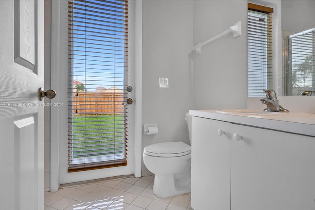 bathroom with tile patterned floors, vanity, a healthy amount of sunlight, and toilet